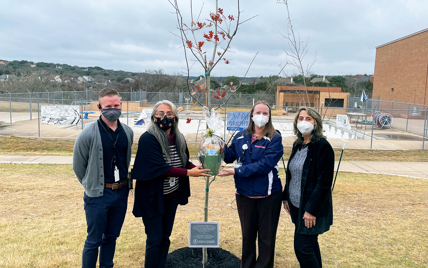 Canyon Vista Middle School Principal Nicole Hagerty and staff stand next to a red oak tree on the Canyon Vista Middle School grounds.